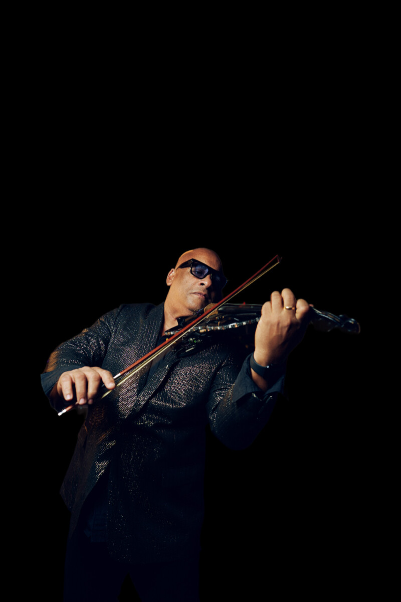 Julio Cuba playing electric violin on stage with dramatic lighting