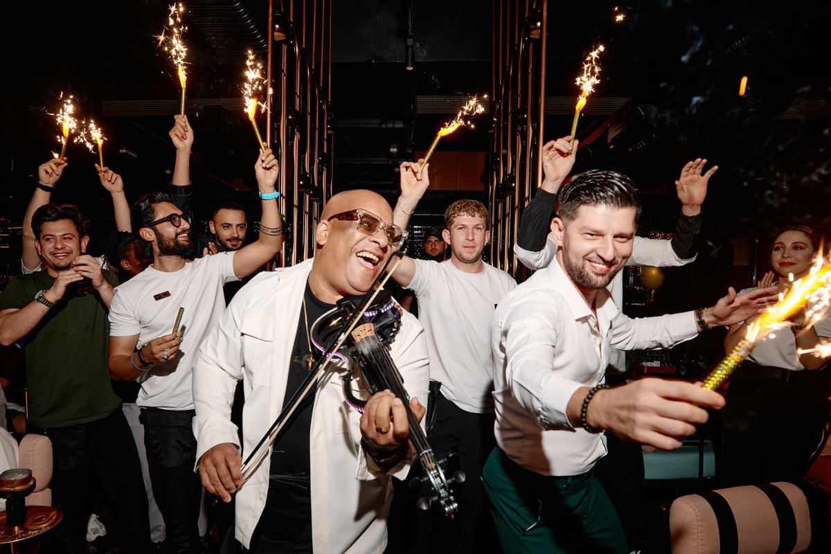Julio Cuba performing electric violin surrounded by sparklers at a luxury club