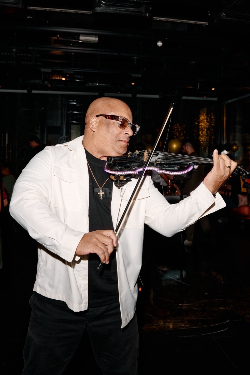 Julio Cuba performing electric violin in white jacket with LED violin