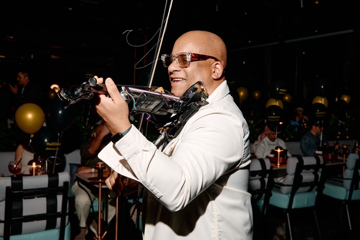 Julio Cuba smiling while playing electric violin at luxury venue